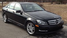 a black mercedes c - class is parked on the side of the road