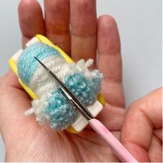 the needle is being used to make an ornament with yarn and wool balls