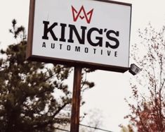 a king's automotive sign with trees in the background