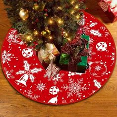 a christmas tree with presents under it on a red placemat that has snowflakes and bells all over it