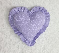 a heart shaped pillow with ruffled edges on a white surface, in the shape of a flower