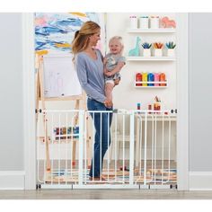 a woman standing next to a baby in a playpen