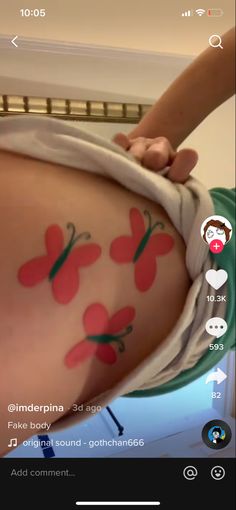 someone is getting their tattoo done on the side of her stomach with red flowers painted on it