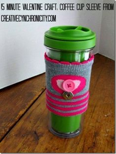 a green cup with a pink heart on it sitting on top of a wooden table