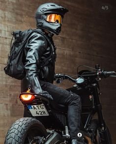 a man sitting on top of a motorcycle wearing a black leather jacket and yellow helmet