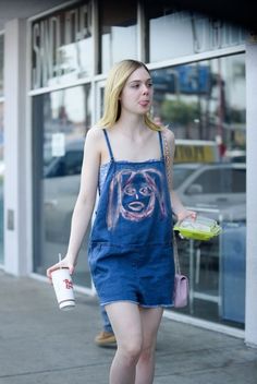 a woman walking down the street with a cup in her hand