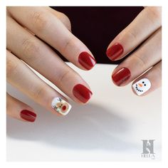 a woman's hands with red and white nail polish on their nails, decorated with snowmen