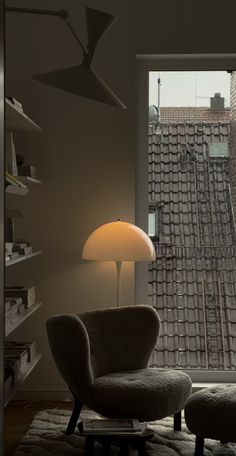 a living room with a chair, lamp and bookcase in front of a window