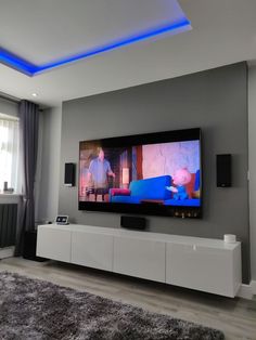 a flat screen tv sitting on top of a white entertainment center next to a window