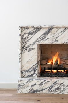 a marble fireplace with logs burning in it