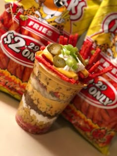 an ice cream sundae with pickles and cheese on top in front of two bags of chips