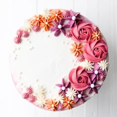 a cake decorated with pink, orange and white flowers