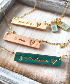 three different necklaces with names on them sitting in a wooden box next to each other