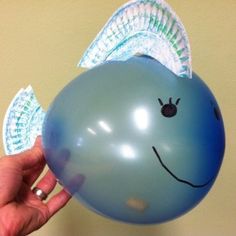 a hand holding a blue balloon with an angel wing on it's head and eyes