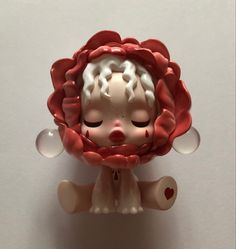 a small figurine with a red flower on it's head and eyes closed