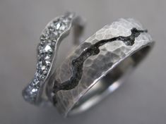 two silver rings with white diamonds on top and one is in the shape of a wave