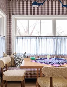 a dining room table with four chairs in front of it and a window behind it