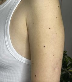 the back of a woman's shoulder with small black dots on her left arm