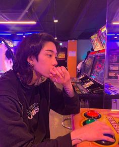 a woman sitting at a table in front of a video game machine with headphones on