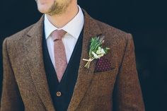 a man wearing a suit and tie with a boutonniere on his lapel