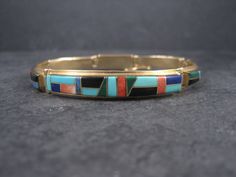 This stunning Native American bracelet is 14k yellow gold. It features inlay in turquoise, denim lapis, coral, lapis lazuli, jet, malachite and spiny oyster. This bracelet measures 3/8 of an inch at the face and tapers down to 1/4 of an inch. It measures 8 inches when clasped and does feature a safety latch. Weight: 22.8 grams Marks: 14K, T Barbre The Barbre family is Cherokee and is known for their gold jewelry. Condition: Phenomenal American Bracelet, Native American Bracelets, Family Jewellery, Spiny Oyster, Italian Charm Bracelet, Chain Link Bracelet, Turquoise Blue, Lapis Lazuli, Chain Link