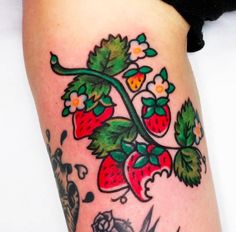 a woman's leg with tattoos on it that has strawberries and flowers on it