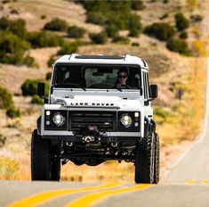 a white land rover is driving down the road