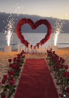 a red carpeted aisle with candles and flowers in the shape of a heart on it