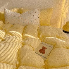 a bed with yellow comforters and pillows on top of it next to a lamp