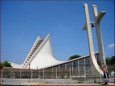 a large white building with a tall cross on it's side next to a fence