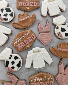 decorated cookies are laid out on a marble counter top, with the words rodeo spelled in pink and white