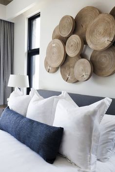 a bed with white pillows and wooden circles on the wall