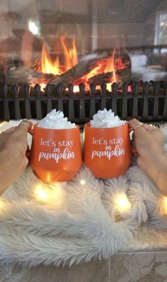 two people holding coffee mugs in front of a fireplace with the words let's stay pumpkin written on them