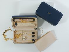 an open purse with jewelry inside it on a table next to a wallet and other items