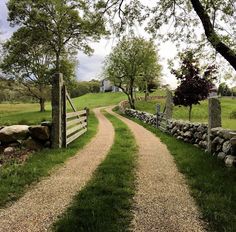 a stone fence and dirt path leading to a grassy field