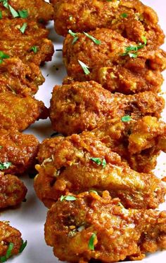 some fried food on a white plate with garnishes and parsley sprinkled