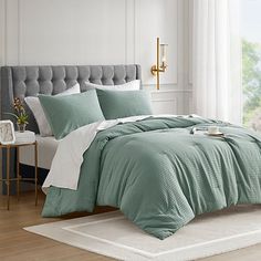 a bed in a bedroom with green comforter and pillows