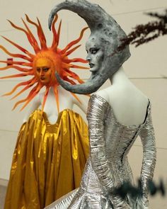 two mannequins dressed in silver and gold, one with a sun on its head