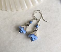 These earrings are made of blue glass flowers, combined with ornate silver decorations. They measure about 1 3/4 inches, or 4.5 cm, including the earring hooks.  All metal is silver-plated. This listing is for one pair of earrings only. Check out the rest of my shop for the other earrings shown in the last photo! https://www.etsy.com/shop/ForbiddenGlade Blue Flower Earrings Nickel Free, Blue Flower-shaped Sterling Silver Earrings, Blue Flower Sterling Silver Earrings, Blue Sterling Silver Flower Earrings For Pierced Ears, Blue Drop Flower Earrings With Ear Wire, Blue Drop Flower Earrings, Handmade Blue Sterling Silver Flower Earrings, Blue Sterling Silver Flower Earrings, Blue Sterling Silver Earrings With French Hook