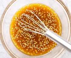 sesame seeds and oil in a glass bowl with a whisk on the side