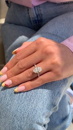 a woman's hand with yellow and pink nails holding a diamond ring