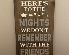 a wooden sign that says here's to the nights we don't remember with the friends