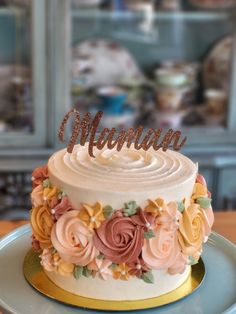 a white cake with flowers and the word mum on top is sitting on a blue plate