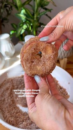 a person holding a donut in their left hand and pointing to it with the other hand