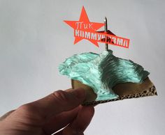 a hand holding a piece of cake with blue frosting and a red star on top