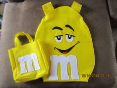 a yellow bag with m and m on it sitting next to a pair of shoes