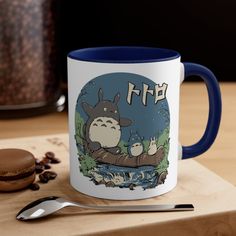 a blue and white totoro coffee mug sitting on top of a wooden table