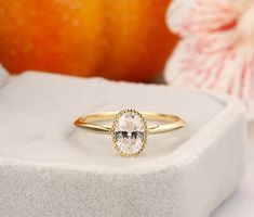 a close up of a ring on a white surface with an orange flower in the background