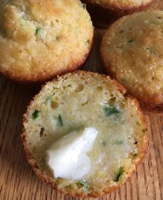 three muffins with cream on top sitting on a wooden table