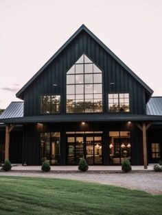 a large black house with lots of windows and grass in the front yard at dusk